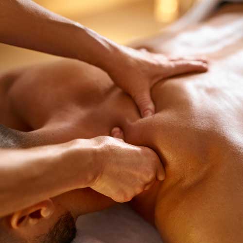 A man getting a massage. A therapist is working his shoulder and back.