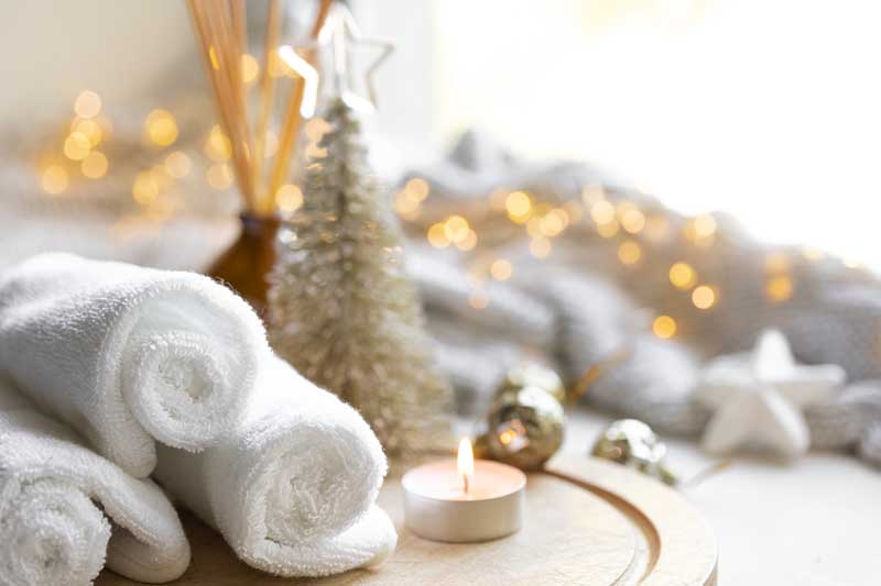 Purchase a gift certificate today! [a photo of towels, aromatherapy items, a candle, twinkle lights and a small decorative pine tree.