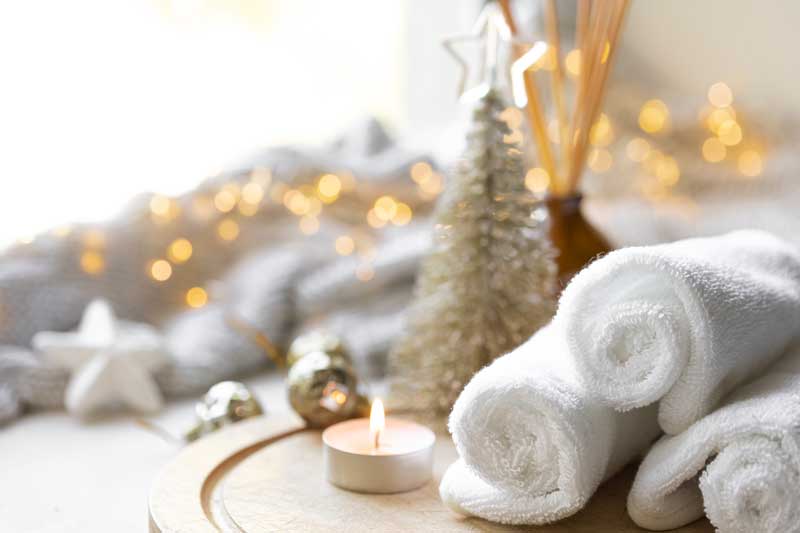 Purchase a gift certificate today! [a photo of towels, aromatherapy items, a candle, twinkle lights and a small decorative pine tree.